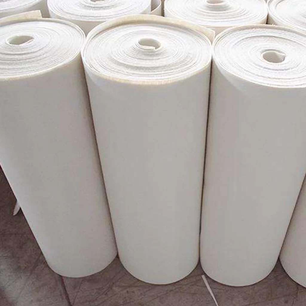 Stos białych rolek włóknin filtrujących w magazynie, podkreślający skuteczność nad bibułami filtracyjnymi w aplikacjach metalurgicznych.